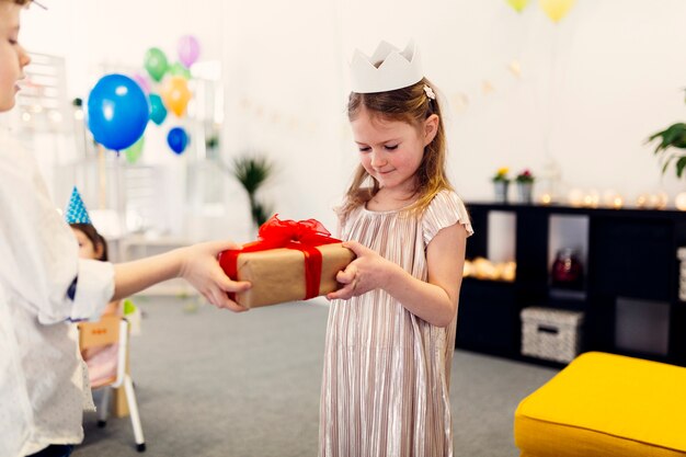 Mädchen in der Kleid- und Papierkrone auf Geburtstag