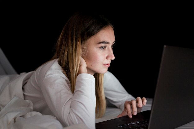 Mädchen in der Nacht im Bett mit Laptop