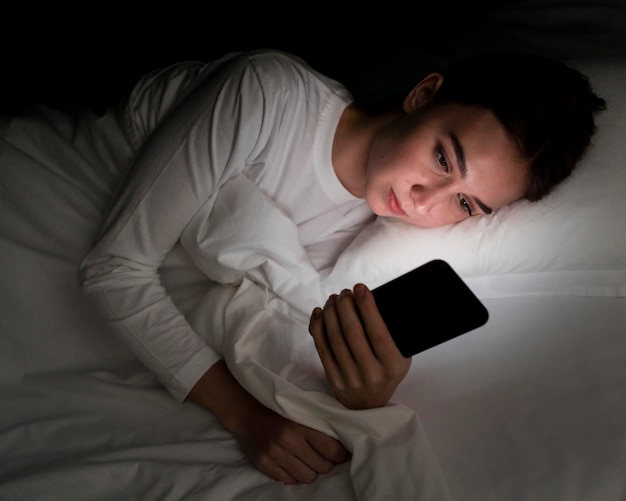 Mädchen in der Nacht im Bett mit Telefon
