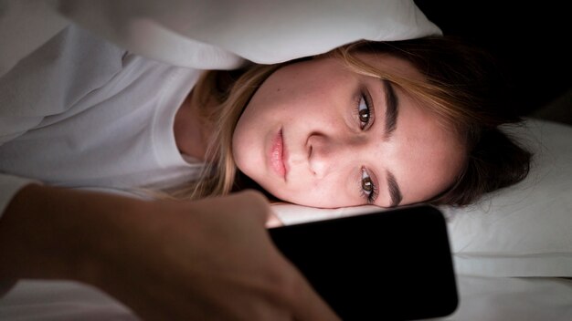 Mädchen in der Nacht im Bett mit Telefonporträt