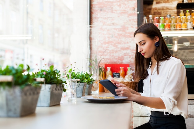 Mädchen in einem Cafe liest etwas auf dem Tablet