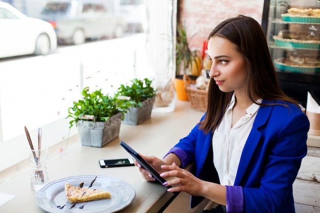 Mädchen in einem Cafe liest etwas auf dem Tablet