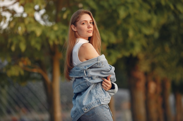 Mädchen in einer blauen Jeansjacke in einer Sommerstadt