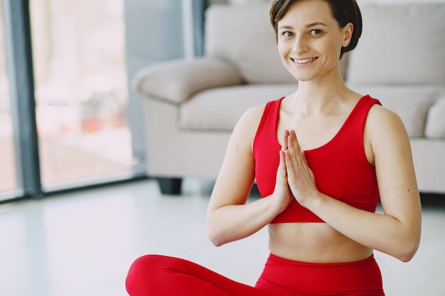 Mädchen in einer roten Sportuniform, die Yoga zu Hause praktiziert