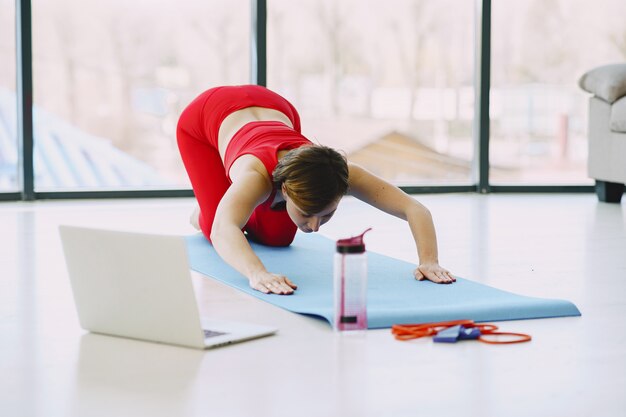 Mädchen in einer roten Sportuniform, die Yoga zu Hause praktiziert