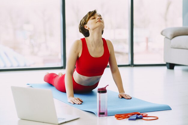 Mädchen in einer roten Sportuniform, die Yoga zu Hause praktiziert
