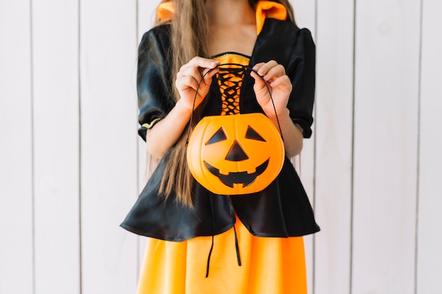 Mädchen in Halloween-Kostüm, das Kürbiskorb hält