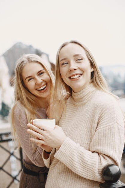 Mädchen in leichten Kleidern. Winterkaffee auf dem Balkon. Glückliche Frauen zusammen.