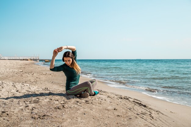 Mädchen in Sportbekleidung Fitness am Meer zuhören