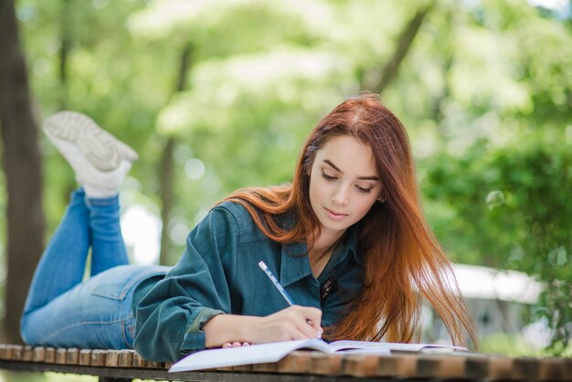 Mädchen liegt auf dem Tisch im Park schriftlich