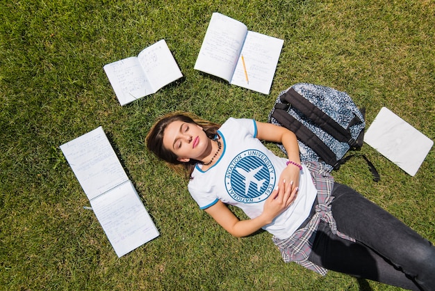 Mädchen liegt auf Gras umgeben von Notebooks