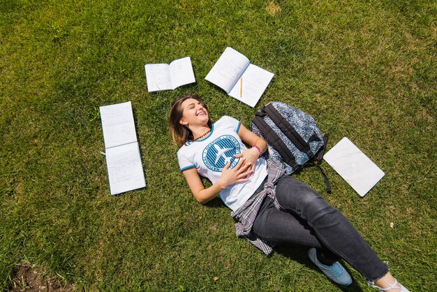 Mädchen liegt auf Gras umgeben von Notebooks