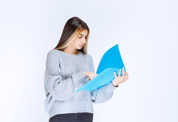 Mädchen liest die Berichte über den blauen Ordner und macht Bemerkungen.