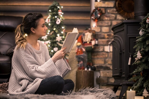 Mädchen liest ein Buch in einer gemütlichen häuslichen Atmosphäre in der Nähe des Kamins