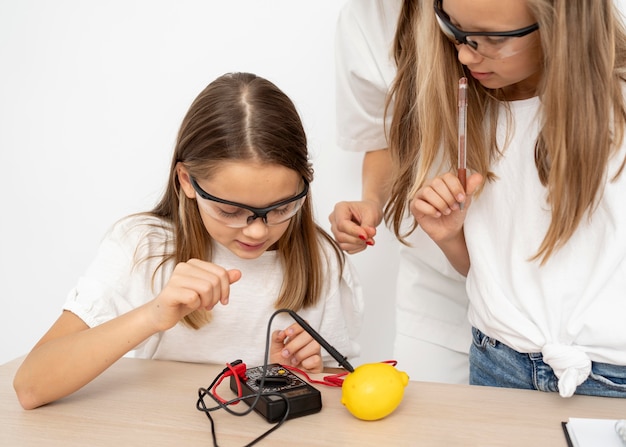 Mädchen machen wissenschaftliche Experimente mit Lehrerin und Zitrone