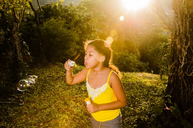 Mädchen macht Seifenblasen mit Sonnenschein-Effekt