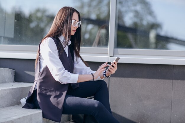 Mädchen mit Brille sitzt auf Treppen an einem mobilen Suche