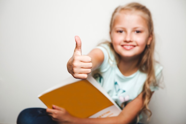 Mädchen mit Buch geben Daumen bis Grinsen