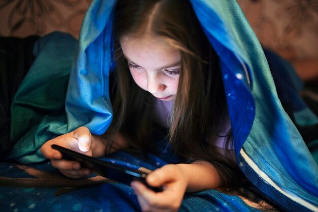 Mädchen mit Decke mit Smartphone
