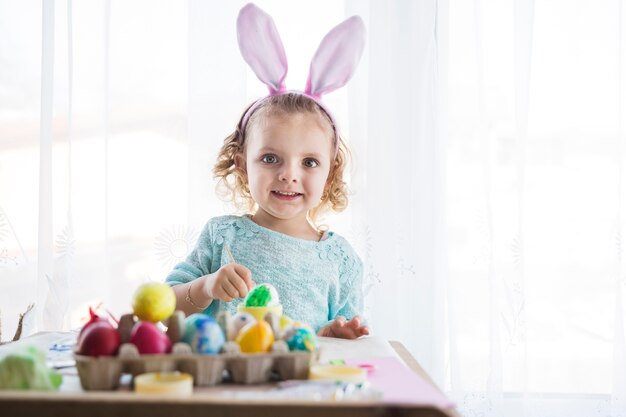 Mädchen mit den Hasenohren, die Eier färben