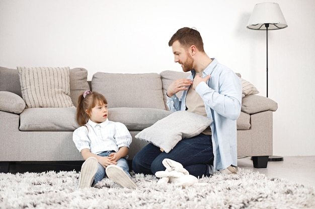 Mädchen mit Down-Syndrom und ihr Vater sitzen auf einem Boden und reden miteinander