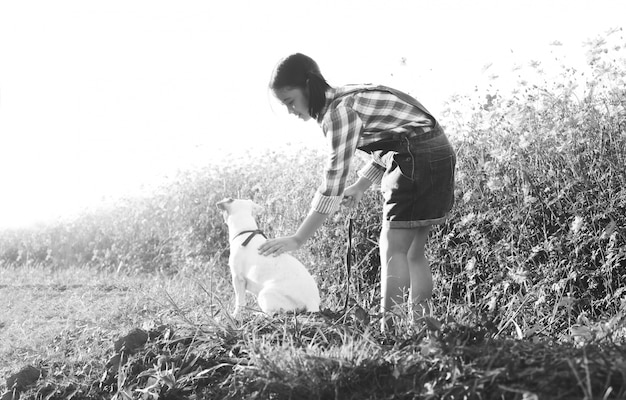 Mädchen mit einem Hund auf dem Gebiet der Blumen.