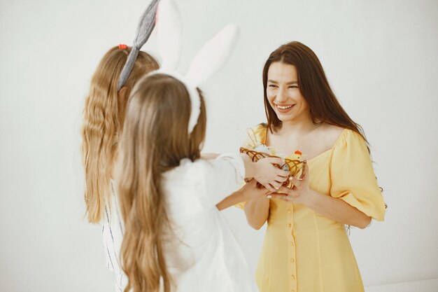 Mädchen mit einem Korb mit Eiern. Glückliche Mutter in einem gelben Kleid. Lange Haare bei Mädchen.