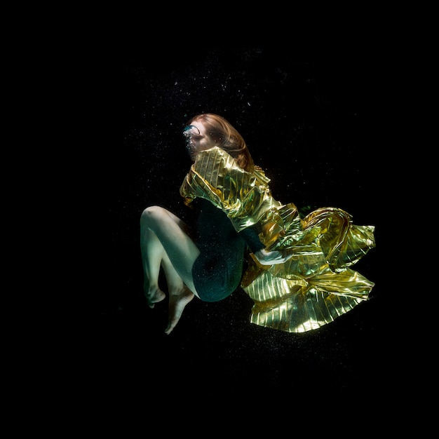 Mädchen mit einem Umhang unter dem Wasser