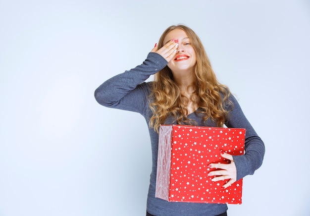 Mädchen mit einer roten Geschenkbox sieht aufgeregt und überrascht aus.