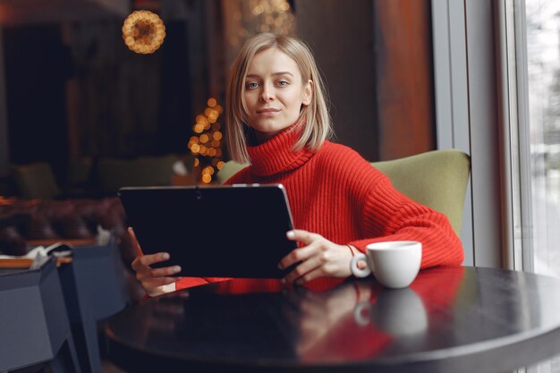 Mädchen mit einer Tablette. Frau in einem Café. Dame sitzt am Tisch.