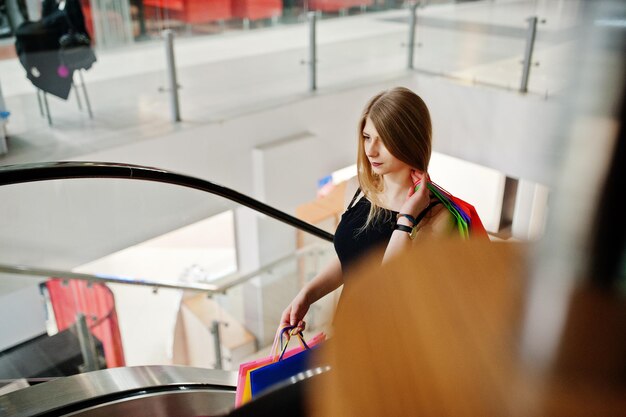 Mädchen mit Einkaufstüten im Einkaufszentrum an der Rolltreppe