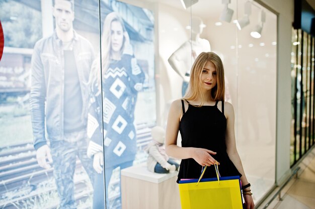 Mädchen mit Einkaufstüten im Einkaufszentrum gegen Mannequins im Schaufenster