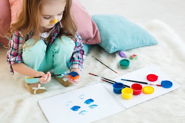 Mädchen mit gelben Nase malt Spielzeug in blauer Farbe