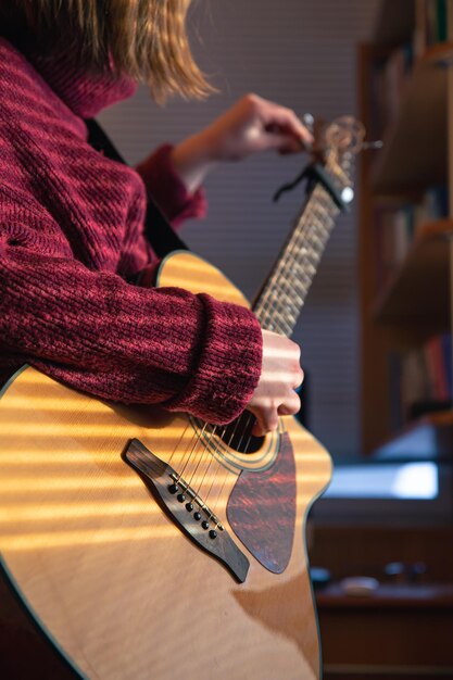 Mädchen mit Gitarre im Sonnenlicht durch die Jalousien