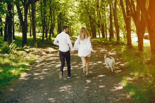 Mädchen mit hellen Haaren in weißen Kleid gekleidet spielt mit ihrem Hund und Freund