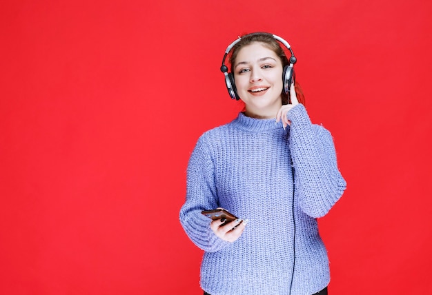 Mädchen mit Kopfhörern, die Musik an ihrem Smartphone einstellen und es genießen.