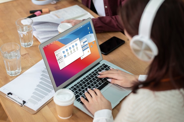 Mädchen mit Kopfhörern mit Laptop zusammen mit ihren Klassenkameraden während des Gruppenstudiums