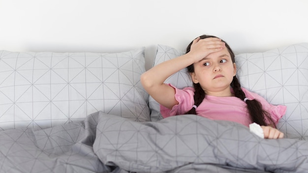 Mädchen mit Kopfschmerzen im Bett liegend
