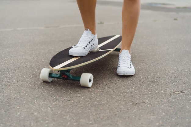 Mädchen mit langen Haaren skates auf einem Skateboard. Straße, aktiver Sport