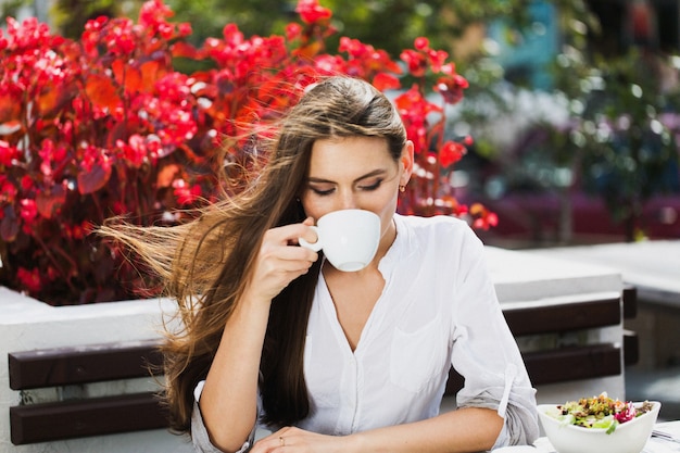 Kostenloses Foto mädchen mit langen haaren trinken kaffee sitzen im restaurant