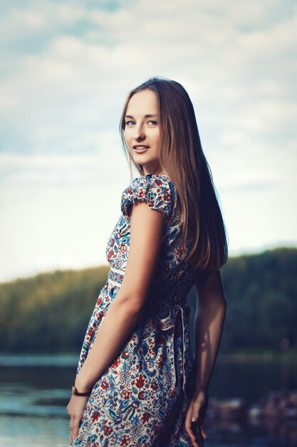 Mädchen mit langen Haaren und Kleid posiert im Freien