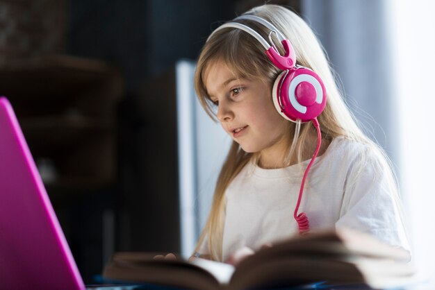 Mädchen mit Laptop hinter offenem Buch