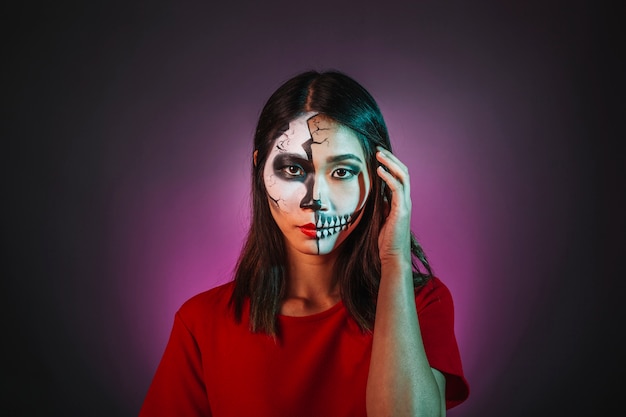 Mädchen mit Make-up und Halloween-Maske berühren ihr Haar