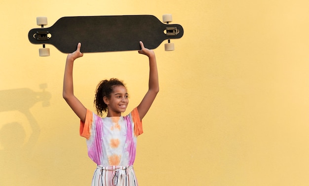 Mädchen mit mittlerem Schuss, das Skateboard hält