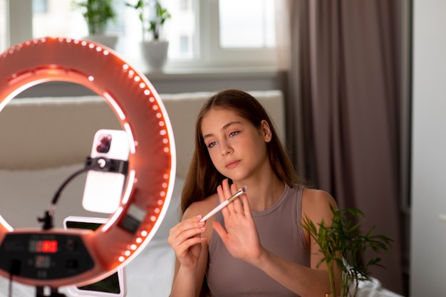 Kostenloses Foto mädchen mit mittlerer aufnahme, das ihre make-up-routine aufzeichnet