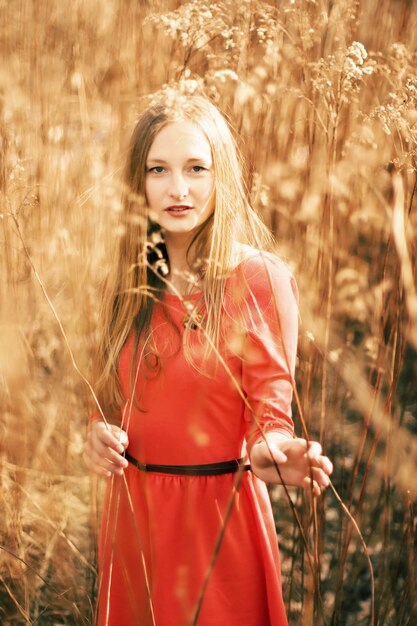 Mädchen mit rotem Kleid und schwarzen Gürtel in der Wiese