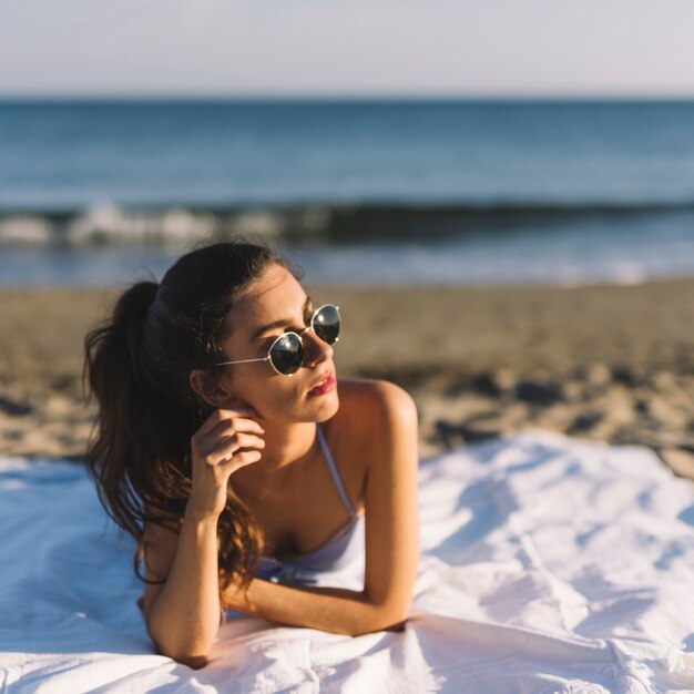 Mädchen mit Sonnenbrille am Strand liegen