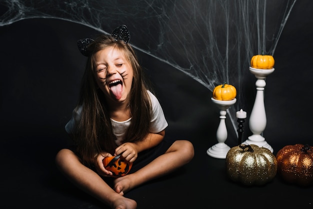 Mädchen mit Süßes sonst gibt's Saures Korb nahe Halloween-Dekorationen