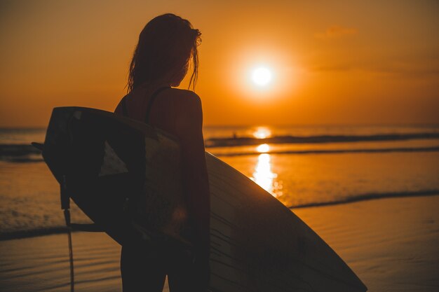 Mädchen posiert mit einem Brett bei Sonnenuntergang