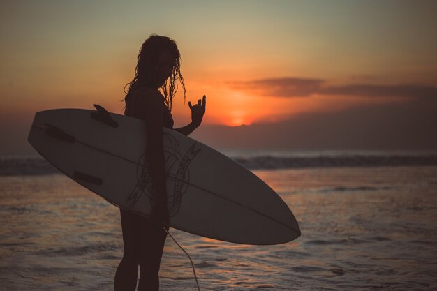 Mädchen posiert mit einem Brett bei Sonnenuntergang